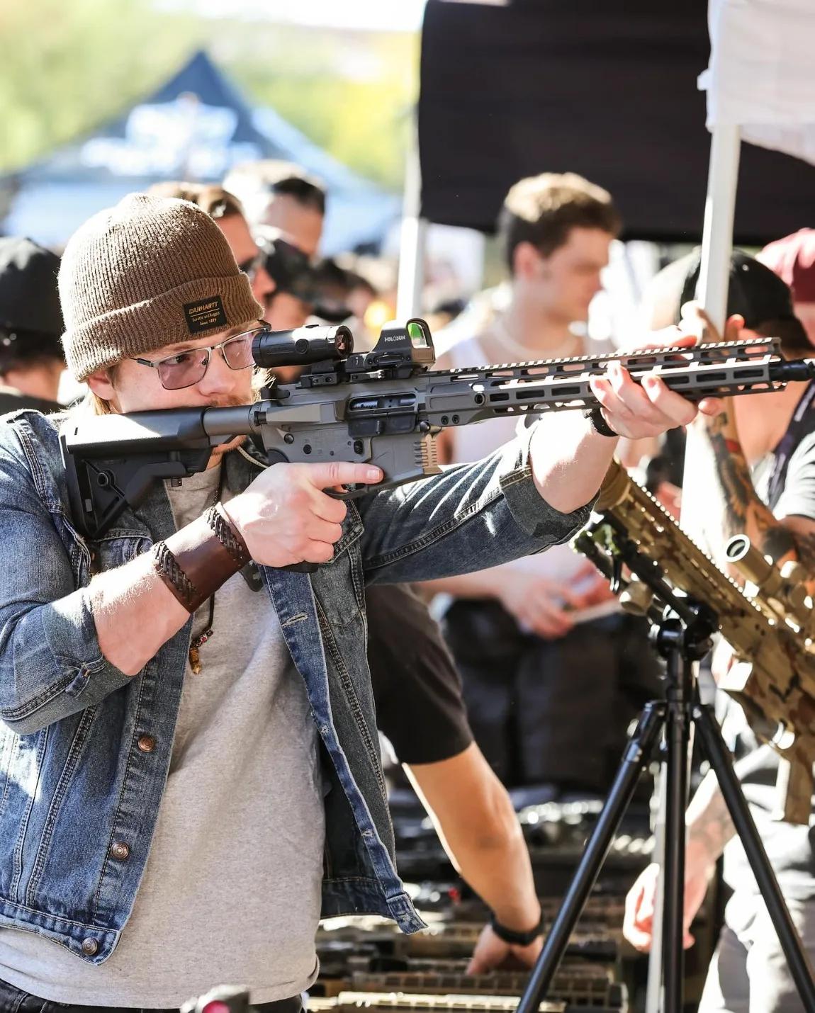 Attendee shouldering a rifle at a vendor booth