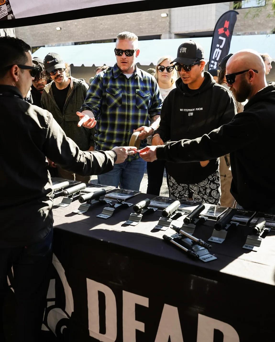 Handshake over a table of pistols at a vendor booth